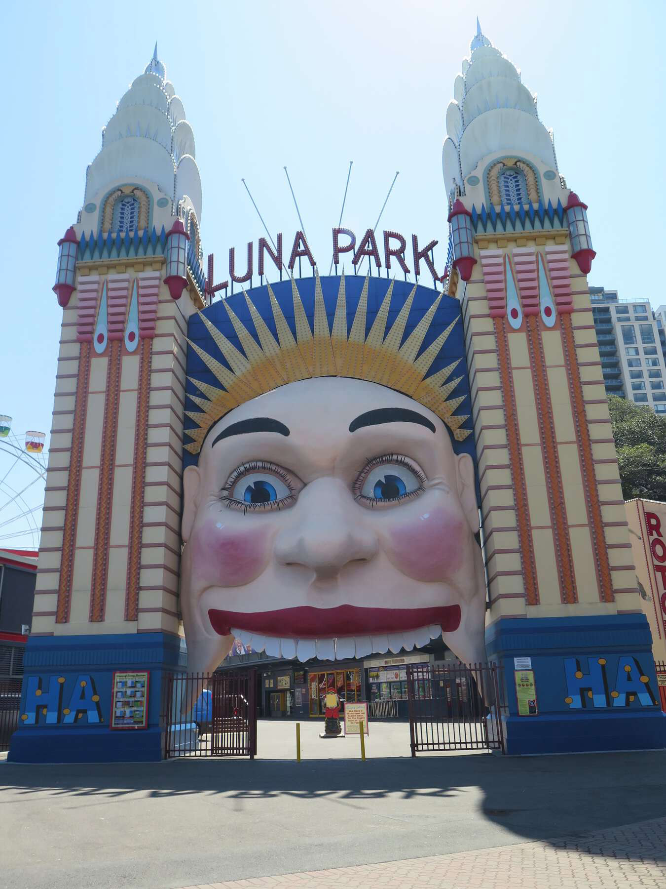 Colorful theme park entrance with an enormous smiling face above and two flanking towers.